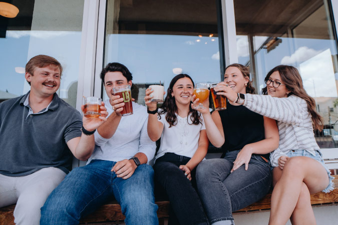 A group of friends cheers with their craft beers on an afternoon out on the town in Lubbock, Texas.
