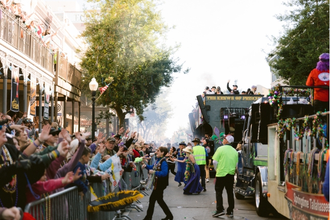 Large Mardi Gras parade floats cruise along city streets as crowds of visitors and locals living in Pensacola cheer from the sidewalks.