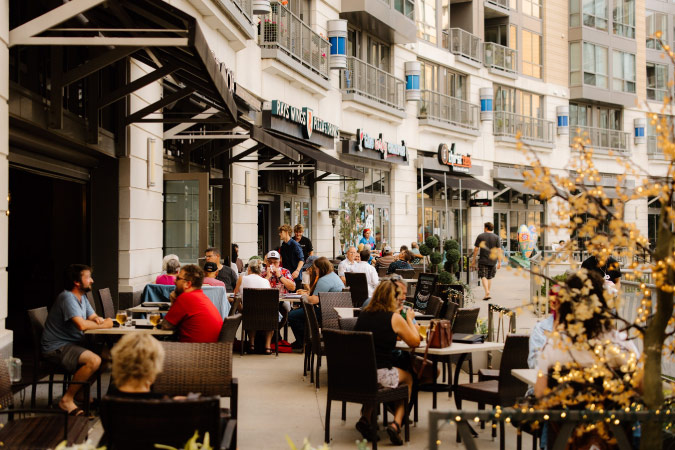 Locals dine al fresco in Midtown Crossing — one of the best Omaha neighborhoods — surrounded by modern buildings used for a mix of commercial and residential purposes.