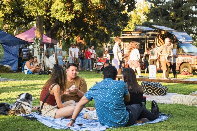 Residents living in Sacramento, CA, enjoy a warm, sunny afternoon on the lawn at an outdoor market festival.