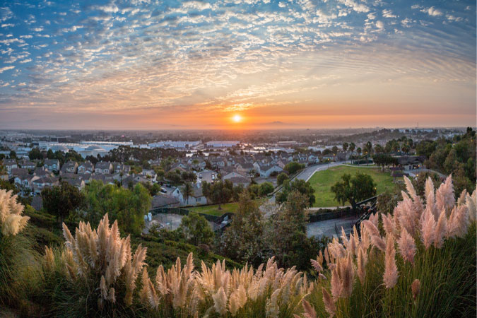 Hilltop view of Signal Hill, California, during sunset, featuring green fields and residential neighborhoods.