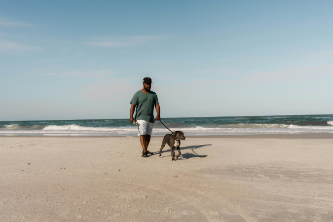 A man walking his dog along Jacksonville Beach.