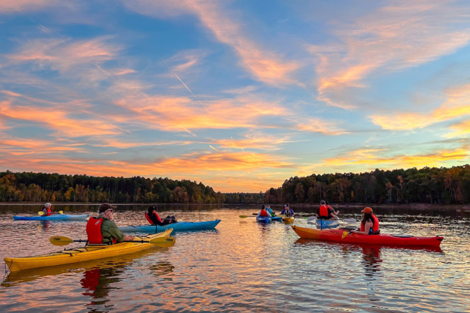 A group of kayakers enjoy sunset on Eno River in Durham, North Carolina.
