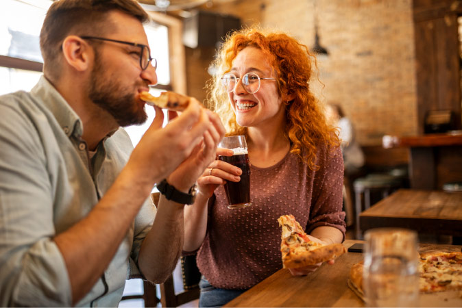 A happy couple is enjoying pizza and beer at a restaurant, something that is easier to do with the affordable cost of living in Lubbock, Texas.