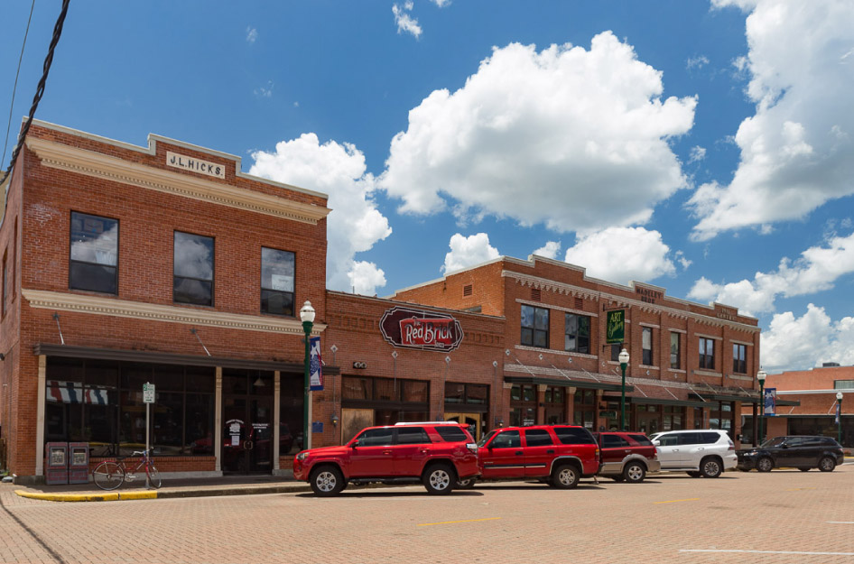 A row of brick commercial buildings in downtown Conroe, Texas, on a sunny day.