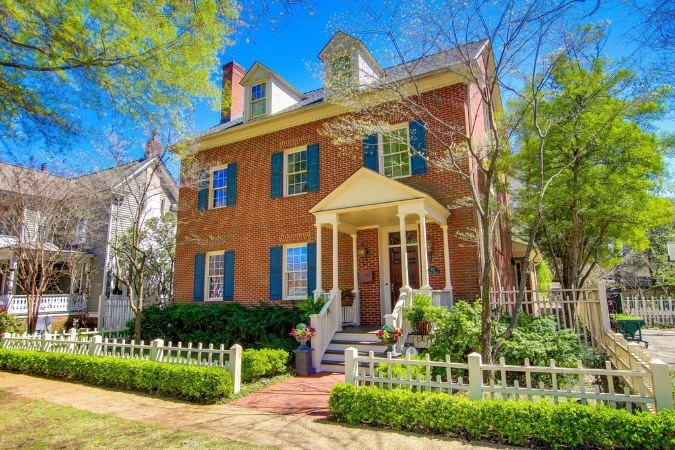 A classic red brick home in the tree-lined Historic District — one of the best places to live in Decatur — featuring blue shutters and a covered front porch.