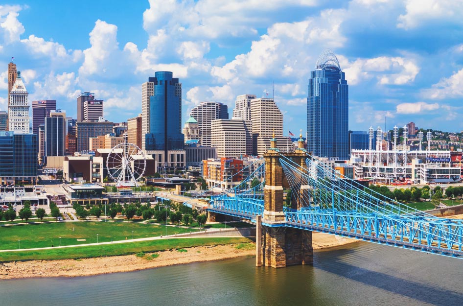 Aerial view of the beautiful Cincinnati skyline on a sunny day, featuring the river and a blue bridge