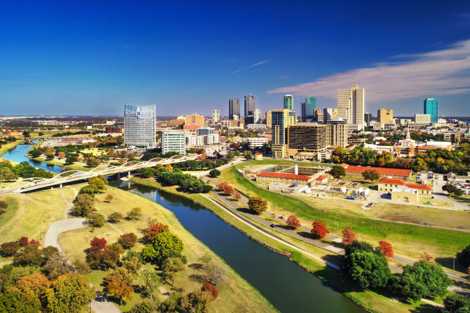 Aerial view of Fort Worth, Texas, on a sunny day with the river running in front of the impressive city skyline.