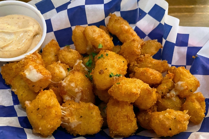 Plate of golden fried cheese curds served with dipping sauce, a beloved local favorite for those living in Wisconsin. 