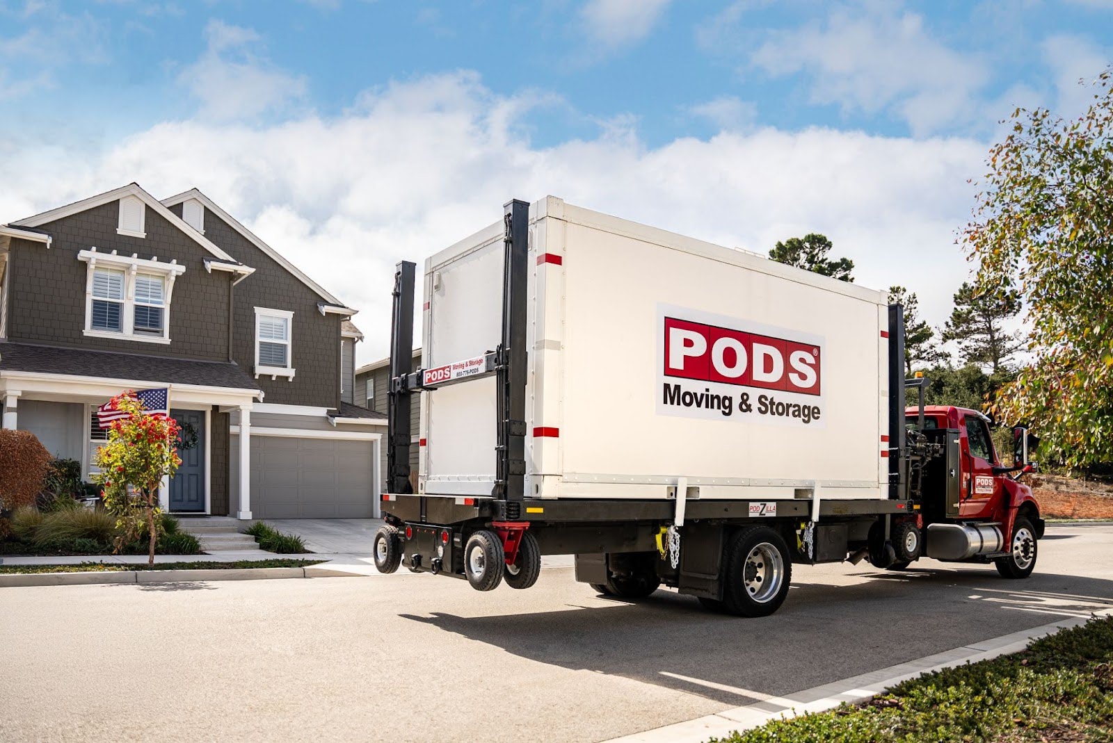 A PODS container on a truck in front of a gray house.