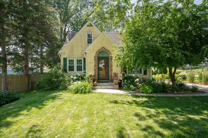 Well-maintained yellow cottage with a landscaped yard and shaded front lawn in one of the inviting Rochester neighborhoods near downtown Rochester