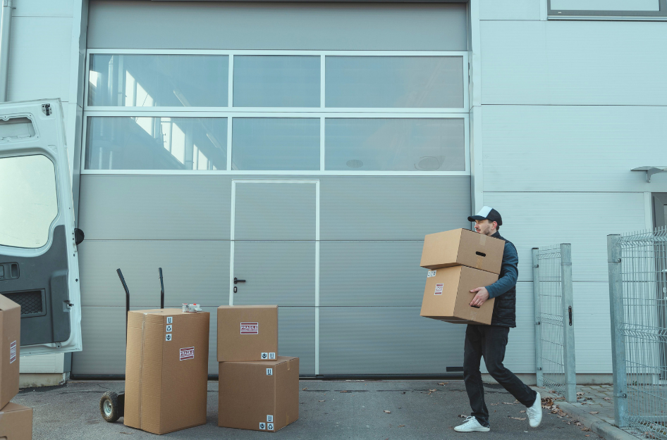 A man carries cardboard boxes into a moving truck after being hired as a commercial mover.