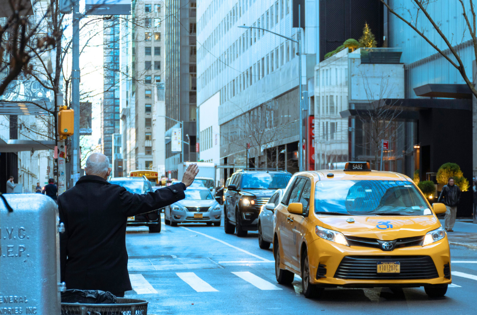 A man hails a taxi cab, a smart way to save money while living in New York city on a budget.