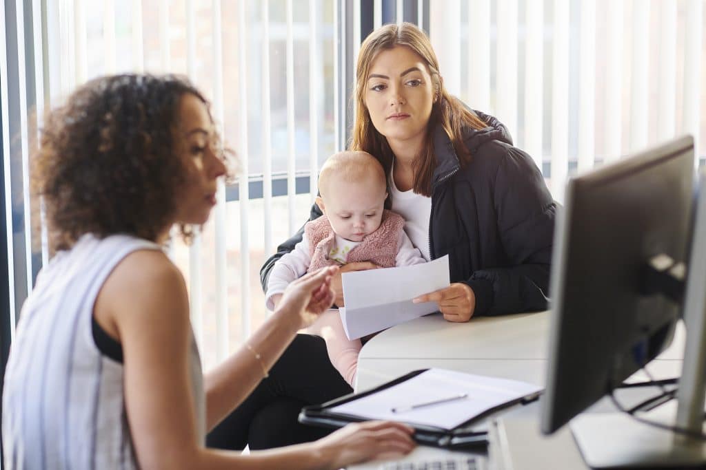 A women holding baby meeting with a social worker