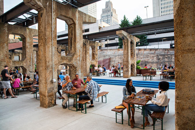 Diners enjoy brews at Incendiary Brewing Company in Winston-Salem, NC, with tables situated under lightrails with a view of the city’s highrises.