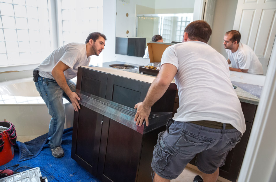 Two men are installing a new vanity during a bathroom remodel