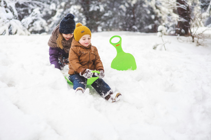 Two young kids play in the snow after their family moved somewhere with a colder climate.