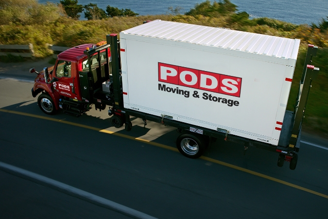 Aerial view of a PODS truck as it transports a portable moving container along a scenic highway — part of a relocation that may qualify for a moving expenses tax deduction.