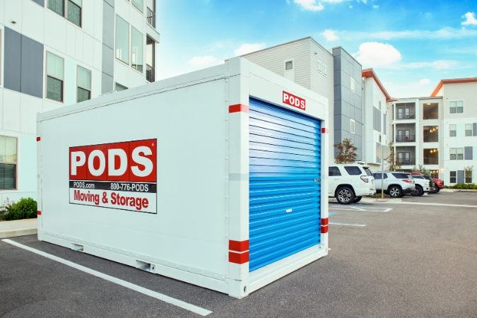 A PODS portable storage container filled with summer storage sits in a parking lot outside of an apartment complex ready to be transported to a PODS Storage Center.