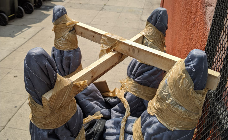 The legs of a wooden chair have been wrapped in moving blankets and secured with wooden beams and packing tape, an example of a packing tip in action.