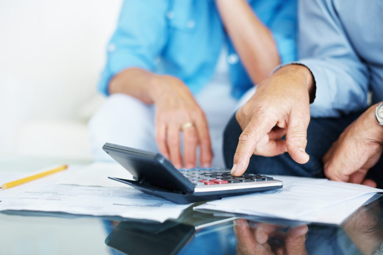 Close-up view of a calculator being used by a senior couple to calculate their retirement savings. 