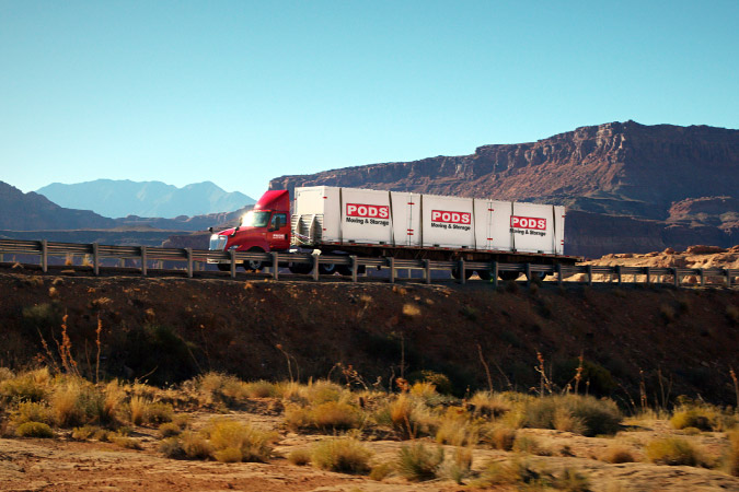 A PODS truck is transporting three portable moving containers through the desert to a residential home in one of the best neighborhoods in Henderson, NV.