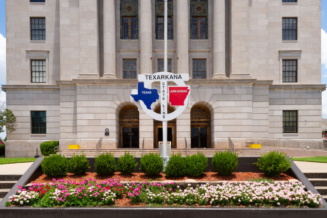 Sunny day view of a sign in Texarkana showing the line of demarcation between Texas and Arkansas.