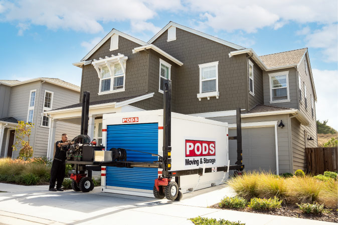 A PODS employee is using PODZILLA to position a PODS portable moving container in a residential driveway.