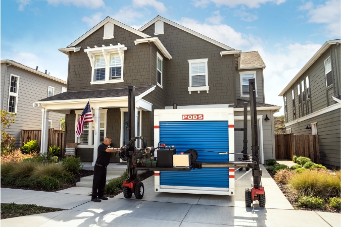 A PODS driver is using PODZILLA to position a portable moving container in a residential driveway for a PCS move.