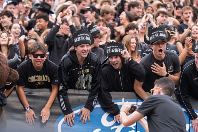 The University of Colorado Boulder stadium is packed with fans in team colors, cheering for the Buffaloes during a home game. 