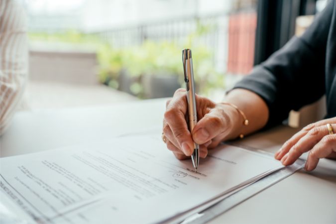A homeowner reviews and signs insurance paperwork to understand coverage for wind damage.