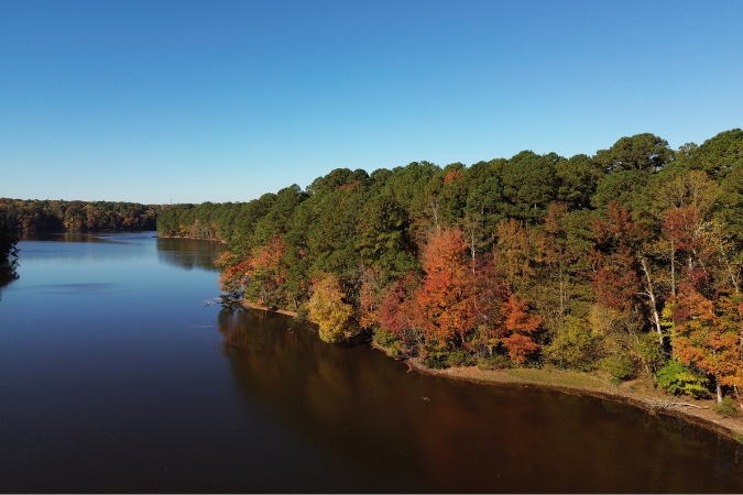 Aerial view of a scenic lake surrounded by colorful fall trees near Greensboro communities in North Carolina.