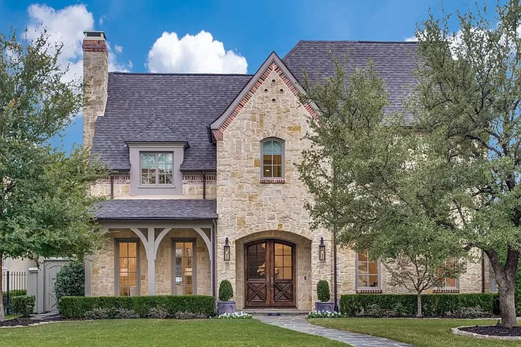 A multi-story home in Caruth Hills in Dallas, Texas. Part of the home is blocked by a green tree in the yard. 