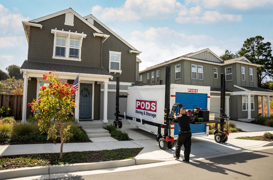 A PODS driver uses PODZILLA to lower a portable moving container into a family’s driveway after ensuring the space meets PODS driveway requirements.