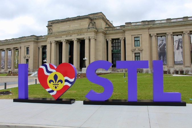 The picturesque “I Love STL” sign stands in the foreground with the Missouri History Museum in the background, capturing the charm of St. Louis neighborhoods nearby.