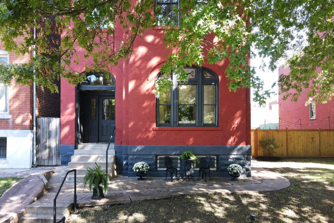 Exterior view of a historic home in Benton Park, St. Louis, made of brick and stone and painted red and black.