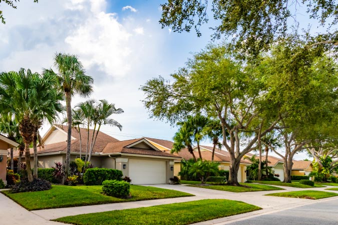 esidential homes in a Florida neighborhood, with stucco exterior, green lawns, and palm trees.