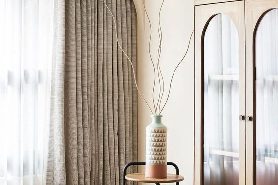 a plain bedroom with a bamboo cabinet and window with coverings. 