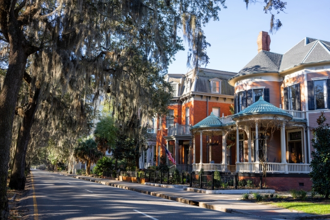 Historic homes shaded by Spanish moss-lined oak trees in Savannah, GA, one of the safest cities in the U.S.