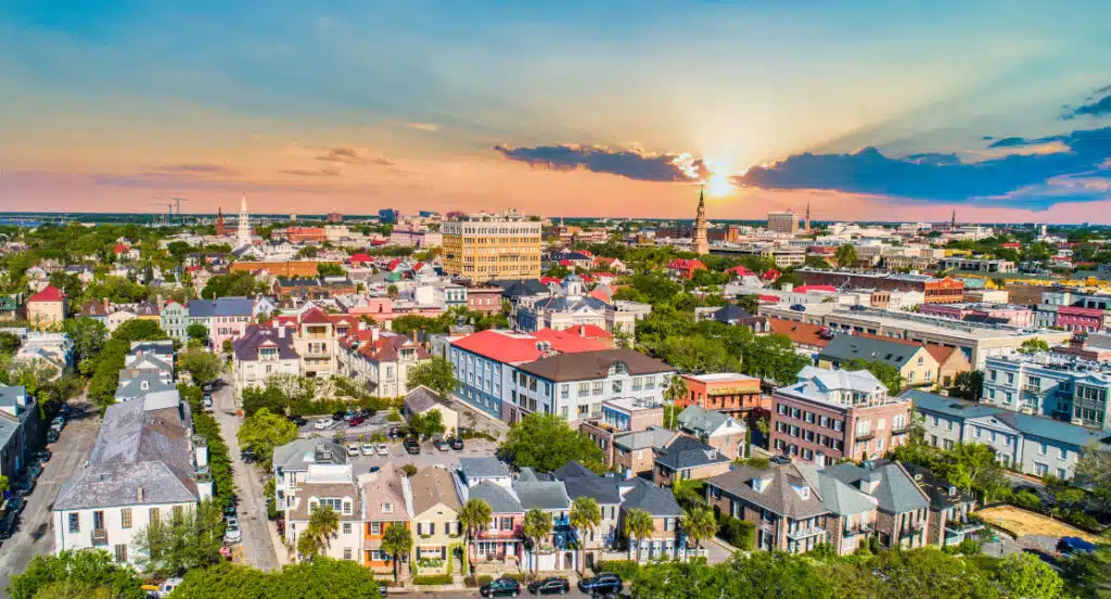 A bird’s-eye view of Charleston, SC, with the sun partially covered by clouds. The steeples that give The Holy City its namesake are visible as far as the eye can see.