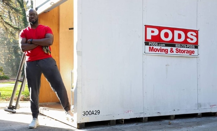 Stacie Walker’s husband, a strong and healthy man, is standing proudly with his arms crossed in front of his PODS storage container. He used the container to securely hold things that are normally kept in his garage to make way for the installation of his new garage gym flooring.
