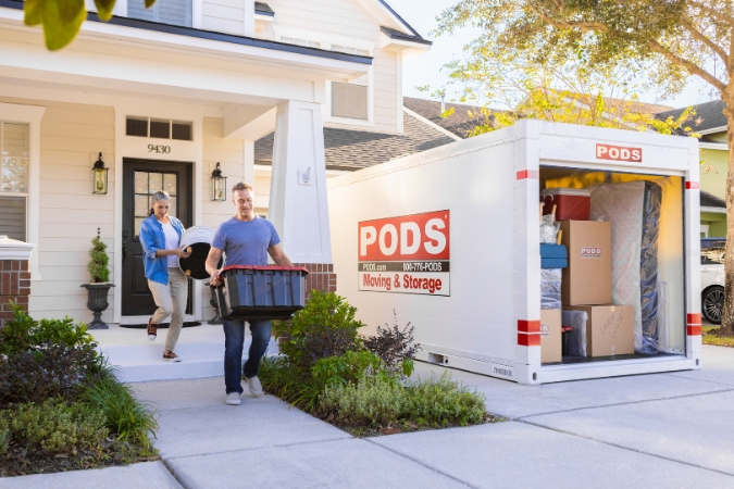 A couple moves belongings into their PODS portable storage container while avoiding what not to put in a storage unit before their move.