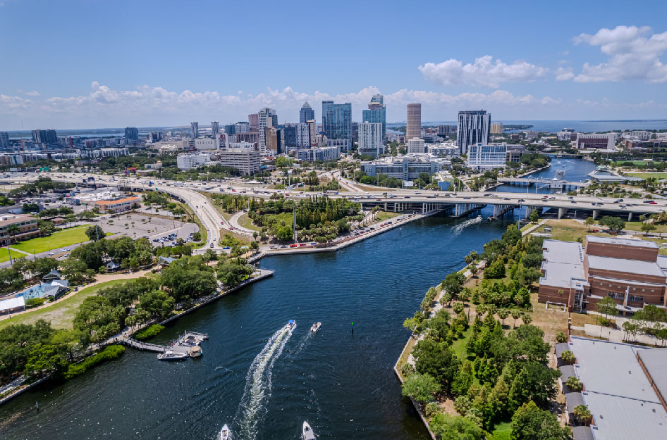 An aerial view of the Tampa skyline with boats traveling through the waterway beside the downtown area.