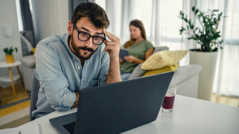 A focused man researches his car shipping options on his laptop.