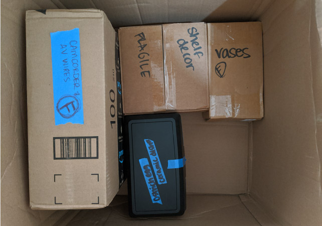 View from above of four small boxes that have been snugly packed inside a larger box — an example of the “Russian doll” packing tip.