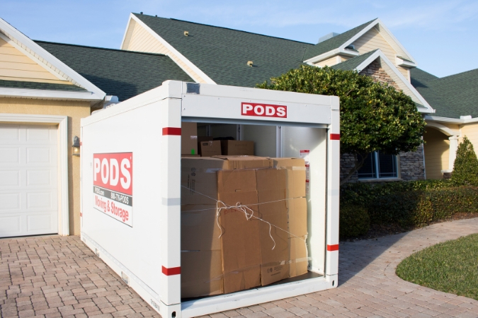 Exterior view of a loaded PODS storage container in a residential driveway, being used for a military move that will involve military moving reimbursement.