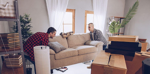 Two men are working together to lift a sofa during a move