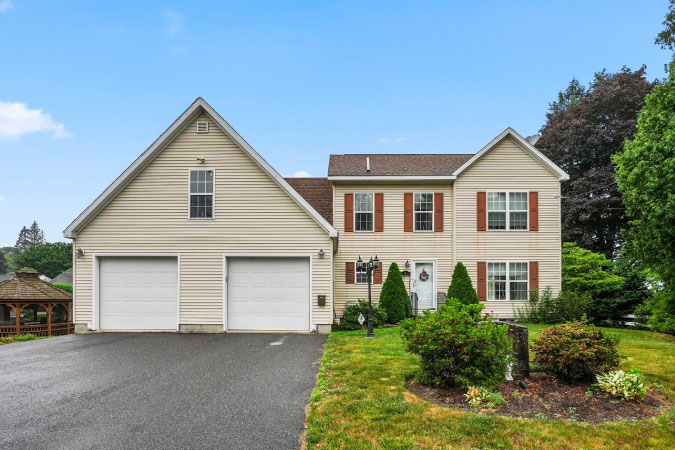 A large home in Grafton Hill — one of the best neighborhoods in Worcester, MA — featuring a two-door garage and a large front lawn.