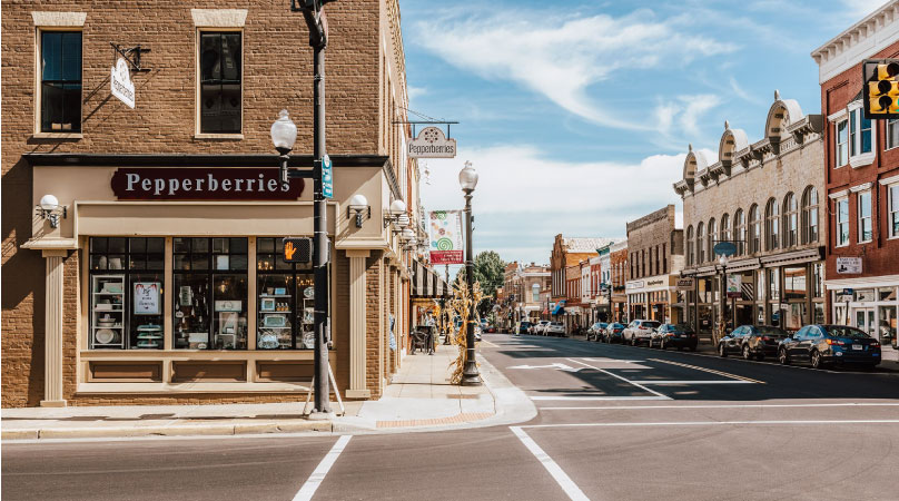 Downtown Culpeper, Virginia, on a sunny day. The streets are lined with brick buildings and a variety of stores and shops.