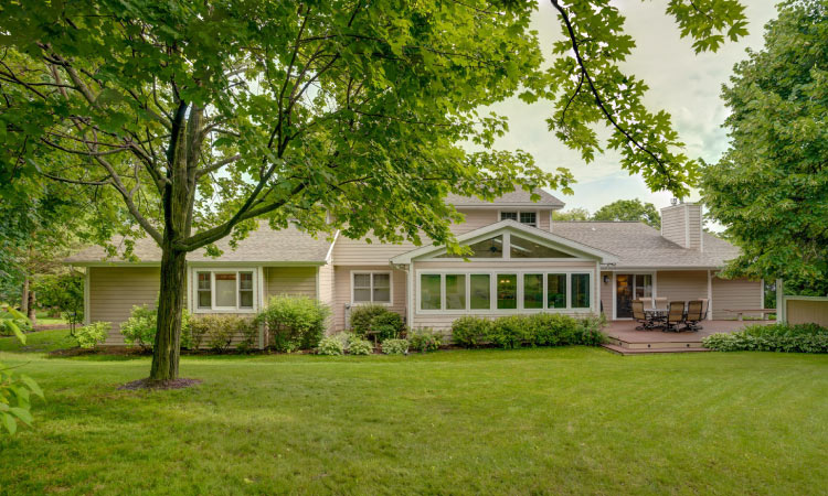 A one-story residential home in the Wexford Village neighborhood of Madison, Wisconsin. The home is painted a light pink shade, and there are large windows letting natural light shine in from the vast yard.